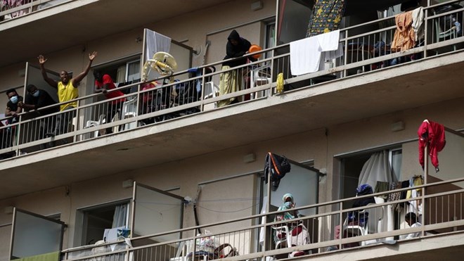 Migrants wave from the their balconies in Kranidi, southern Greece, on Tuesday. Authorities confirmed a high number of COVID-19 infections at the site. Thanassis Stavrakis/AP