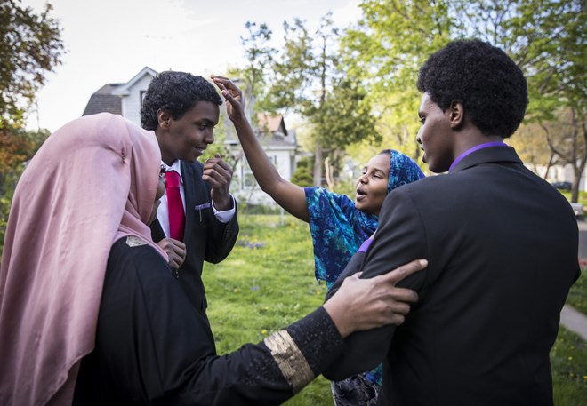 Mohamed Hassan's mother Amino A. Farah, left, and sister Fardowsa Hassan, in blue, doted over him and his brother Ali Hassan, right, in their suits as they came outside to take pictures with them before Mohamed's senior prom on May 6, 2017 at home in Columbia Heights, Minn. Renee Jones Schneider