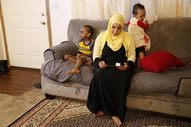 Amina Olow, a refugee from Somalia, looks at photos of two of her eldest daughters while siting with two of her other children in her Columbus, Ohio, home on Friday, Feb. 23, 2018. The girls, Neemotallah, now 12, and Nastexo, now 9, live in Kenya with other family members. It has been 10 years since their mother has seen them. "I never thought it would be this long," Olow says of her separation from her daughters, who she hopes can join her despite the fact that Somalia is on a list of countries impacted by the Trump administration travel ban. (AP Photo/martha Irvine)
