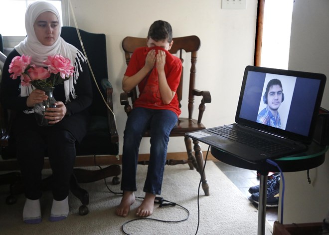 Ten-year-old Syrian Amjud Moustafa Rifat uses his shirt to wipe away tears on Tuesday, Feb. 20, 2018, in Columbus, Ohio, as he and his 18-year-old sister, Fatima, listen to a song their brother, Hasib, wrote for the family. Hasib, 16, is still in the Middle East and has been separated from his family for more than 18 months as he awaits a U.S. visa. Their father, Rifat Moustafa, an international lawyer who says he was tortured for protesting human rights violations, was granted asylum and his wife and four other children followed in 2016, before President Trump was elected. They were hoping Hasib could come shortly after, but resettlement officials say the Trump administrationвЂ™s travel ban on refugees from mostly Muslim countries has very likely caused further delays. (AP Photo/martha Irvine)